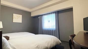 A hotel room with a bed, a desk, and a chair.