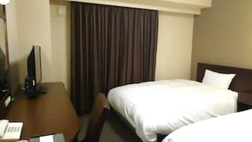 Una habitación de hotel con escritorio, dos camas, teléfono y televisor.