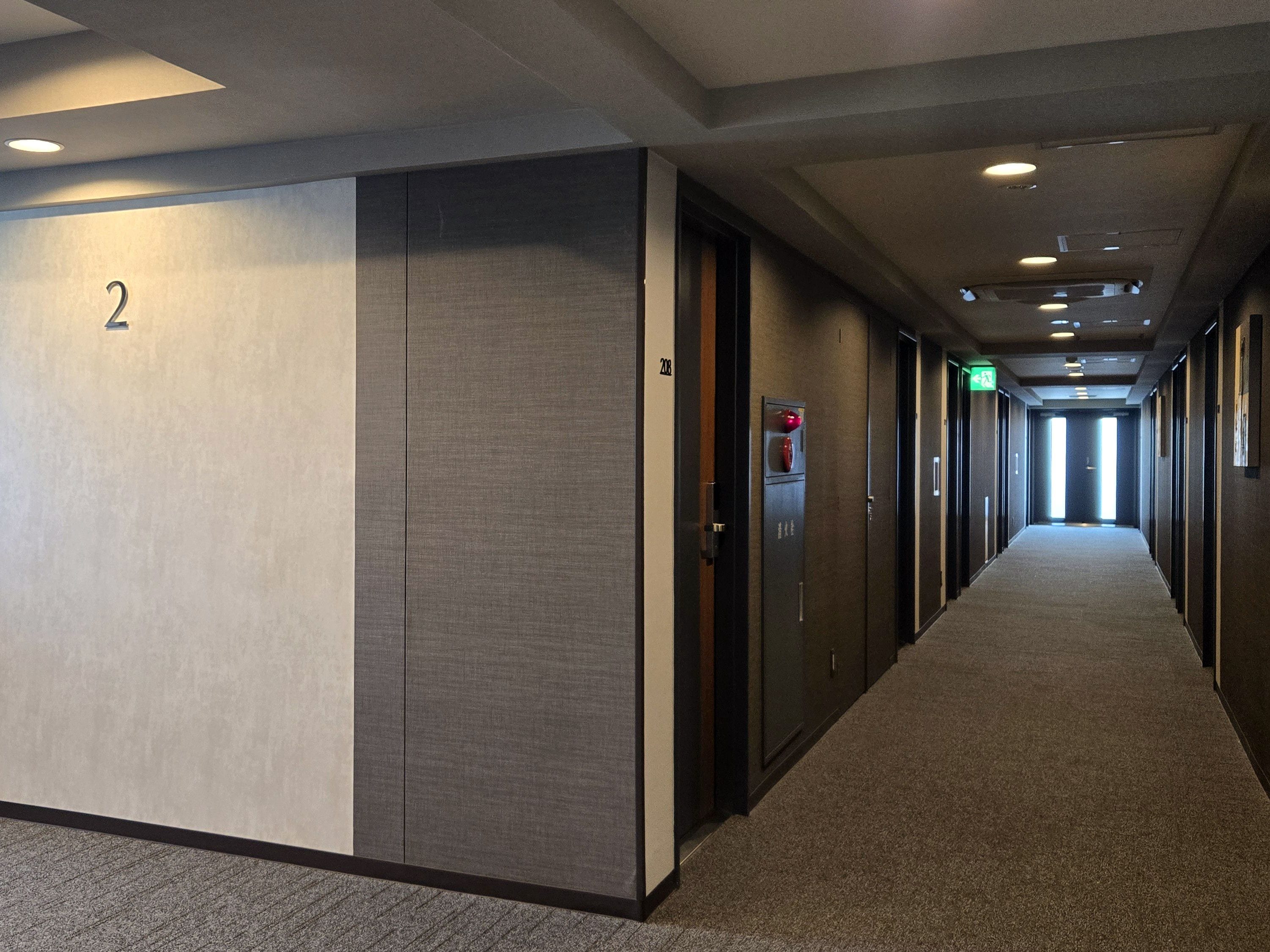 Pasillo de hotel con puertas, piso alfombrado y el número 2 en la pared.
