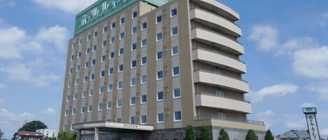 Hotel com vários andares e uma placa verde grande no topo.