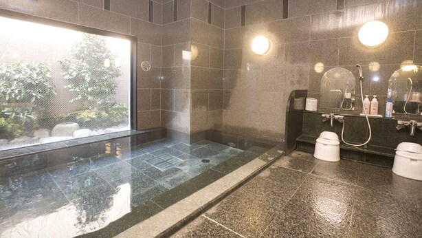 Un baño moderno con ducha de vidrio, un espejo grande y un lavamanos con artículos de aseo.