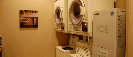 A laundry area with two front-loading washing machines and a dryer stacked on top of each other.