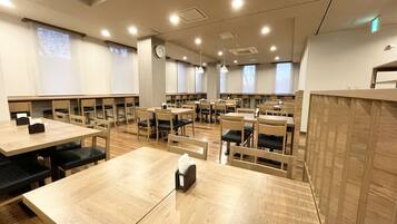 A spacious dining area with multiple tables and chairs, equipped with ceiling lights and a clock on the wall.