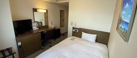 A hotel room with a bed, a desk with a computer, a television, and a painting on the wall.