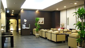 Un hall d’hôtel comprenant un comptoir d’accueil, un espace salon et des plantes en pot.
