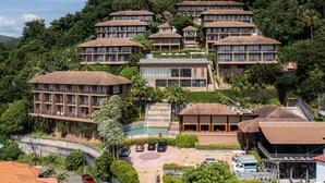A multi-story hotel with a central courtyard, surrounded by lush greenery and hills. - Karon Phunaka Resort (Karon)