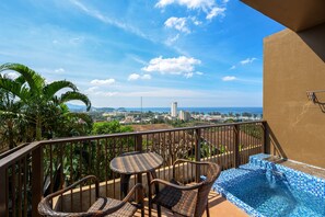 A balcony with wicker furniture, a small pool, and a view of the city and ocean. - Karon Phunaka Resort (Karon)