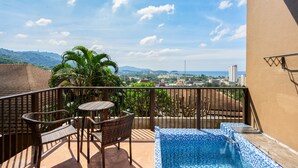 A balcony with a small pool, wicker furniture, and a view of the city and mountains. - Karon Phunaka Resort (Karon)