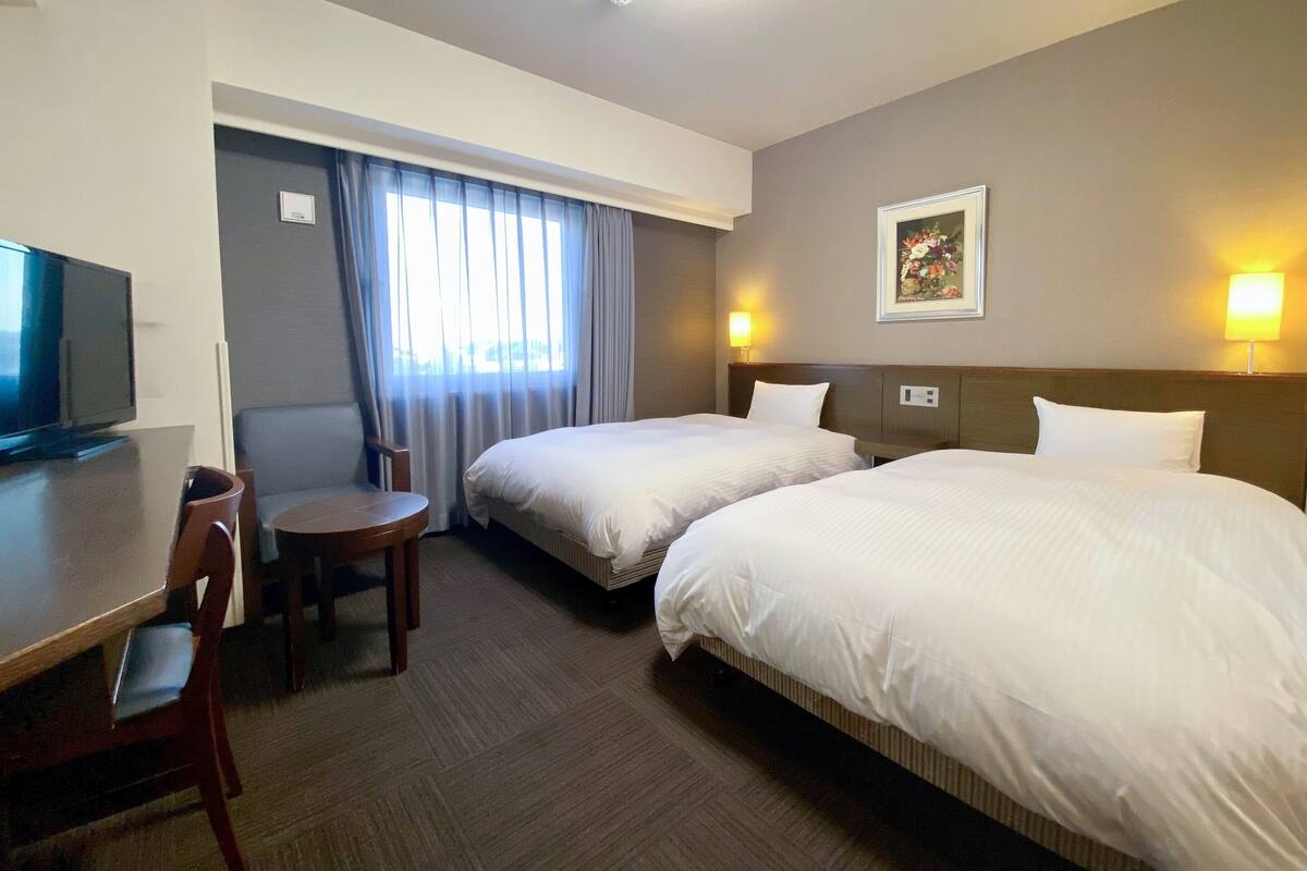 Ett hotellrum med två sängar, en TV, ett skrivbord och en stol.