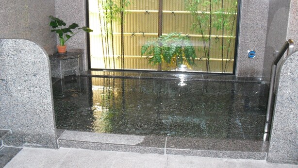 A spa area with a large mirror reflecting a bamboo screen and a potted plant.