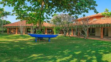 A courtyard with a blue boat, surrounded by buildings with red-tiled roofs and covered seating areas.