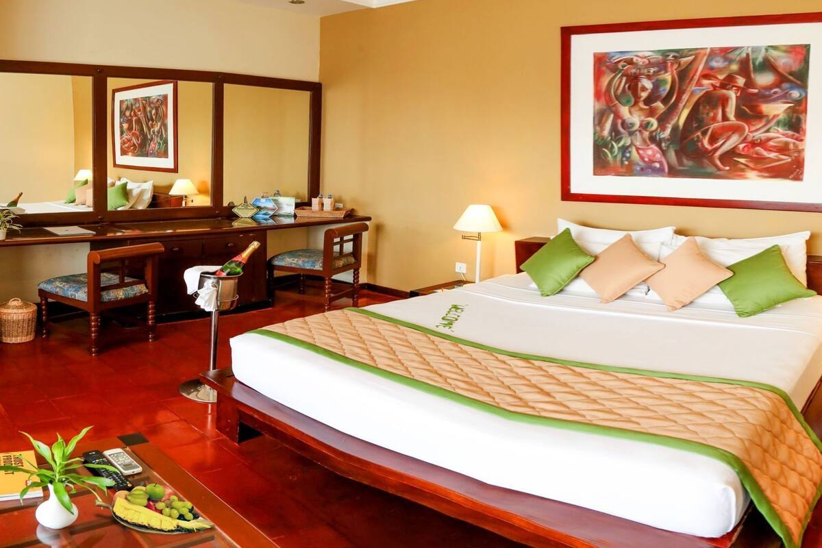 Une chambre d’hôtel avec un lit, un bureau, une chaise et un tableau au mur.