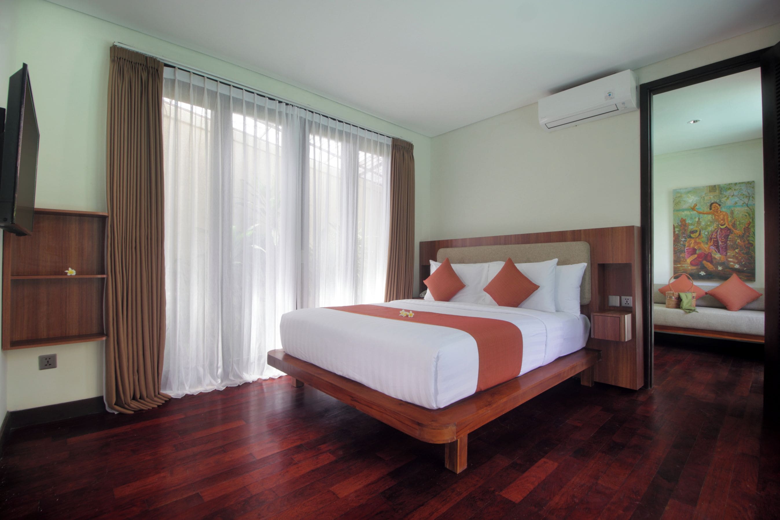 Habitación de hotel con cama de madera, ropa de cama blanca, mesita de noche de madera, televisor y un cuadro en la pared.
