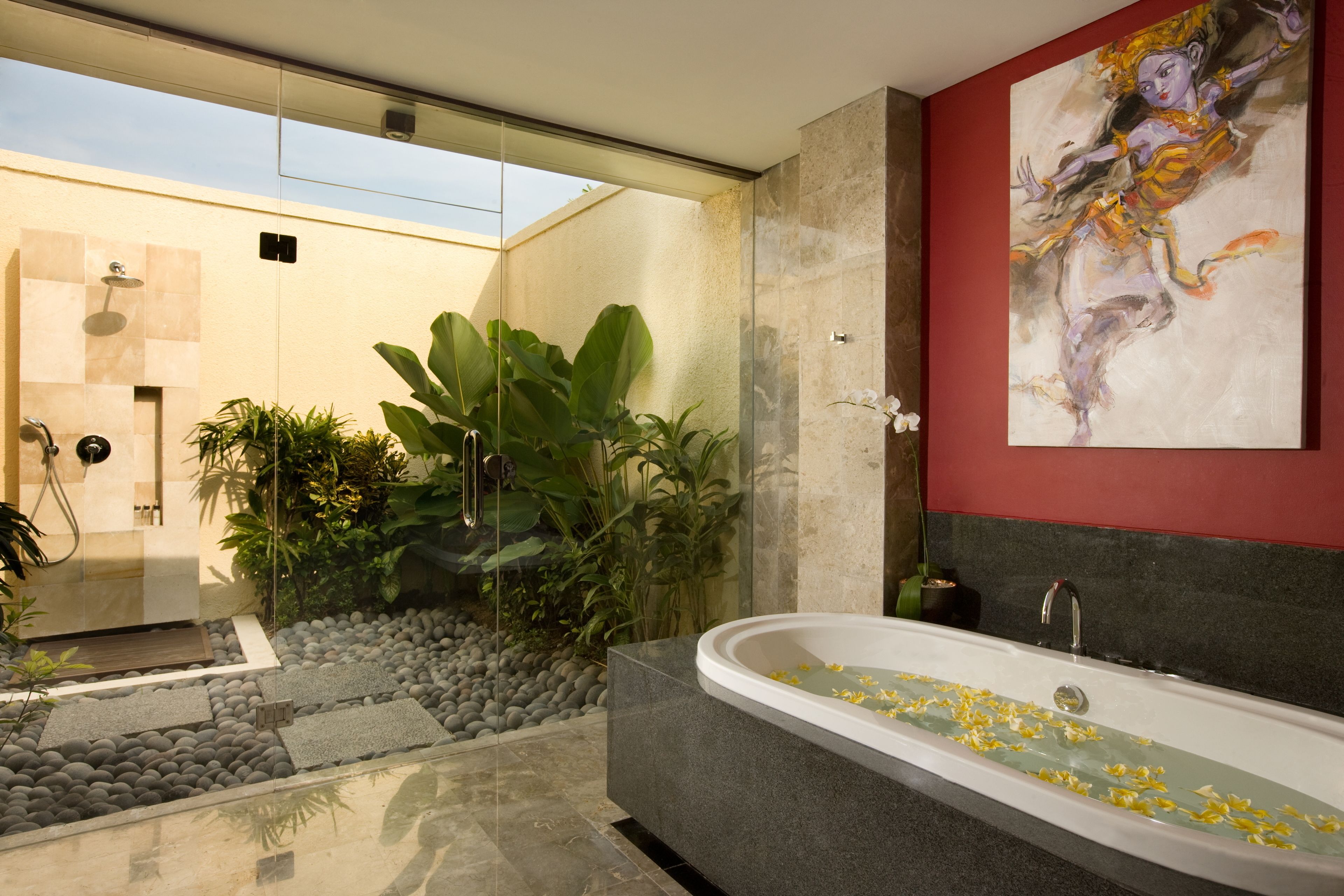 Un baño moderno con una bañera independiente, una zona de ducha y una planta grande en maceta.