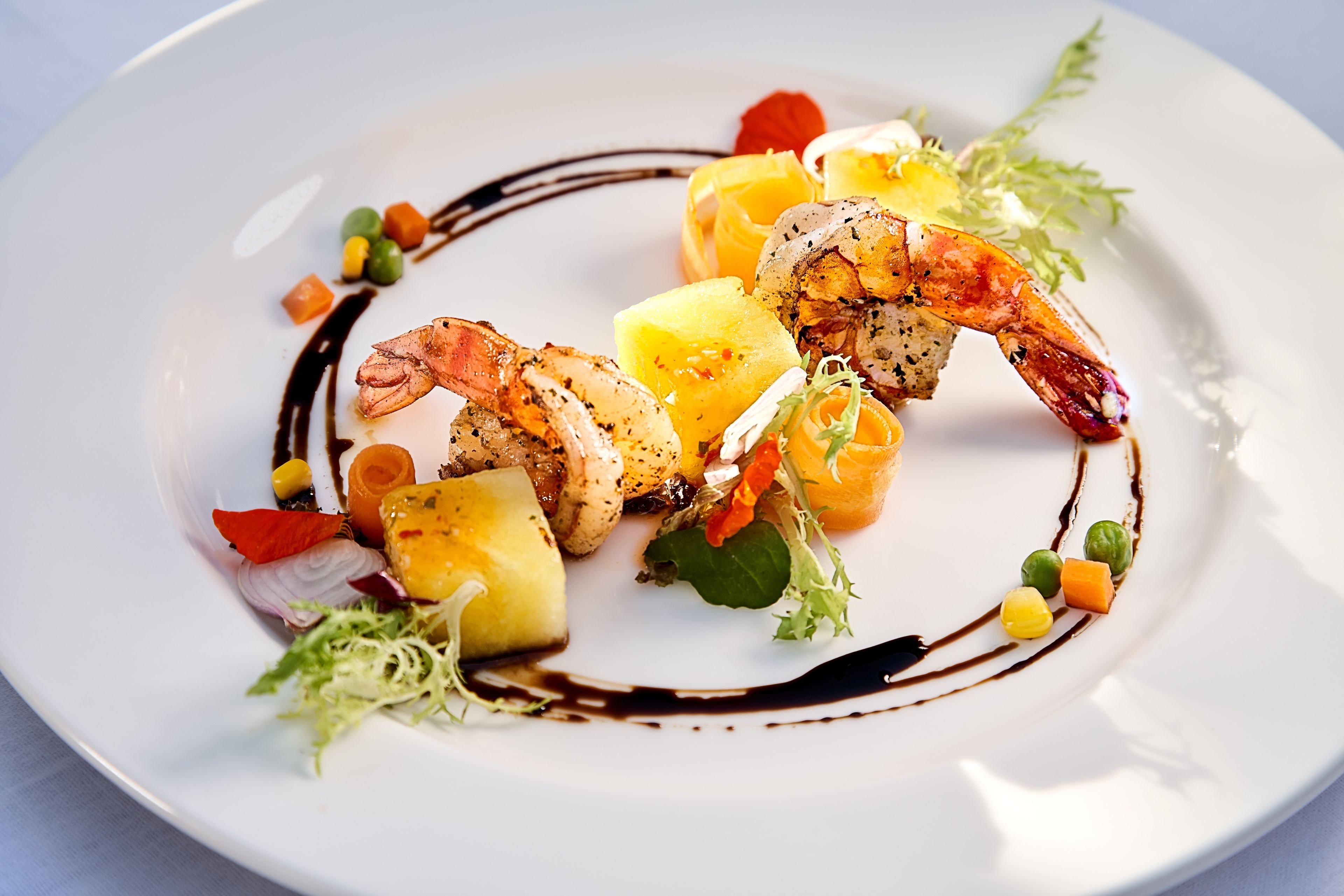 A plate of food with shrimp, vegetables, and a sauce.
