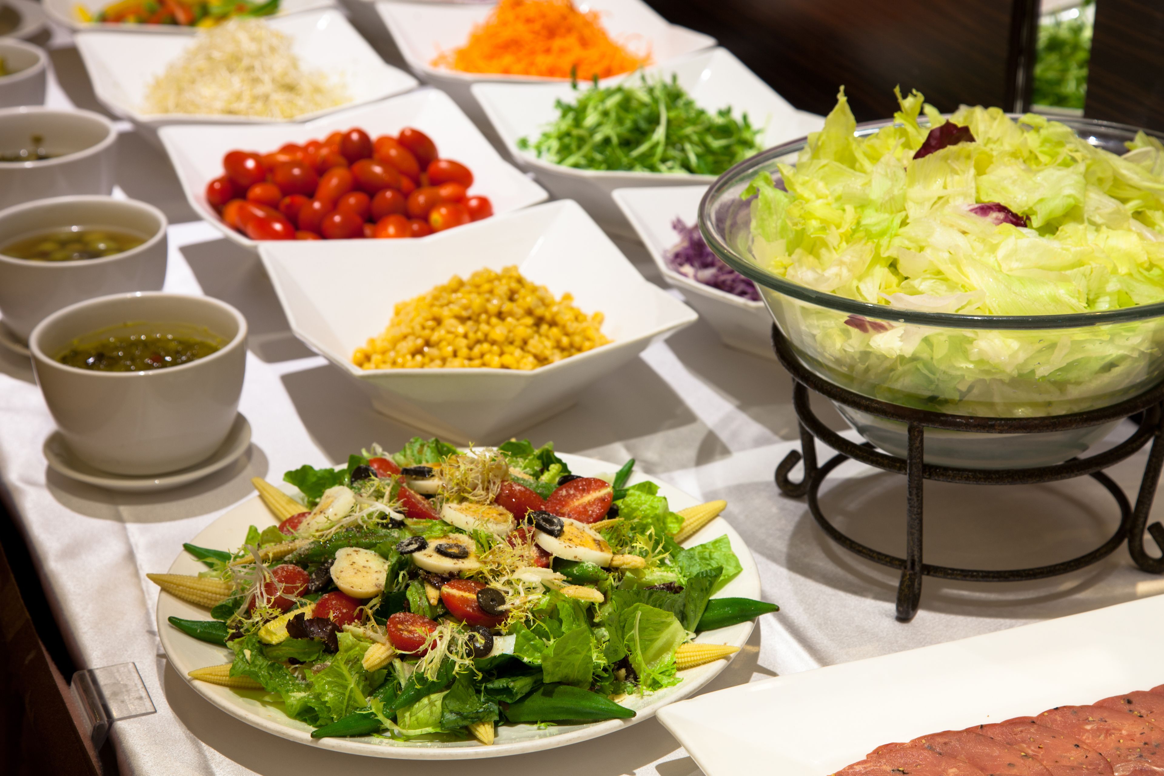 Una mesa de buffet con diversos alimentos, como ensaladas, verduras y cereales.