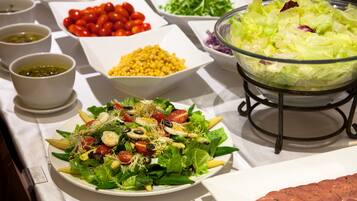 Una mesa de buffet con diversos alimentos, como ensaladas, verduras y cereales.