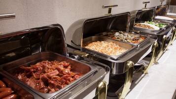 Buffet com diversas opções de comida, incluindo carnes e saladas.