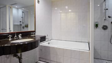A modern bathroom with a large mirror, a sink, a bathtub, and a shower area.