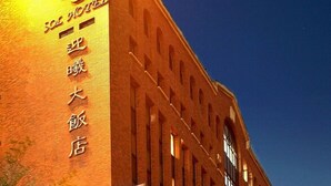 Un grande edificio in mattoni con finestre ad arco e un cartello ben visibile.