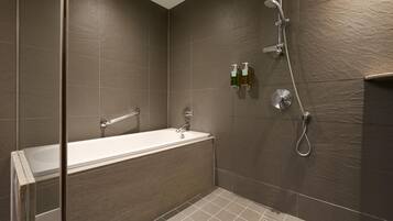 A modern bathroom with a bathtub, shower, and two soap dispensers on the wall.