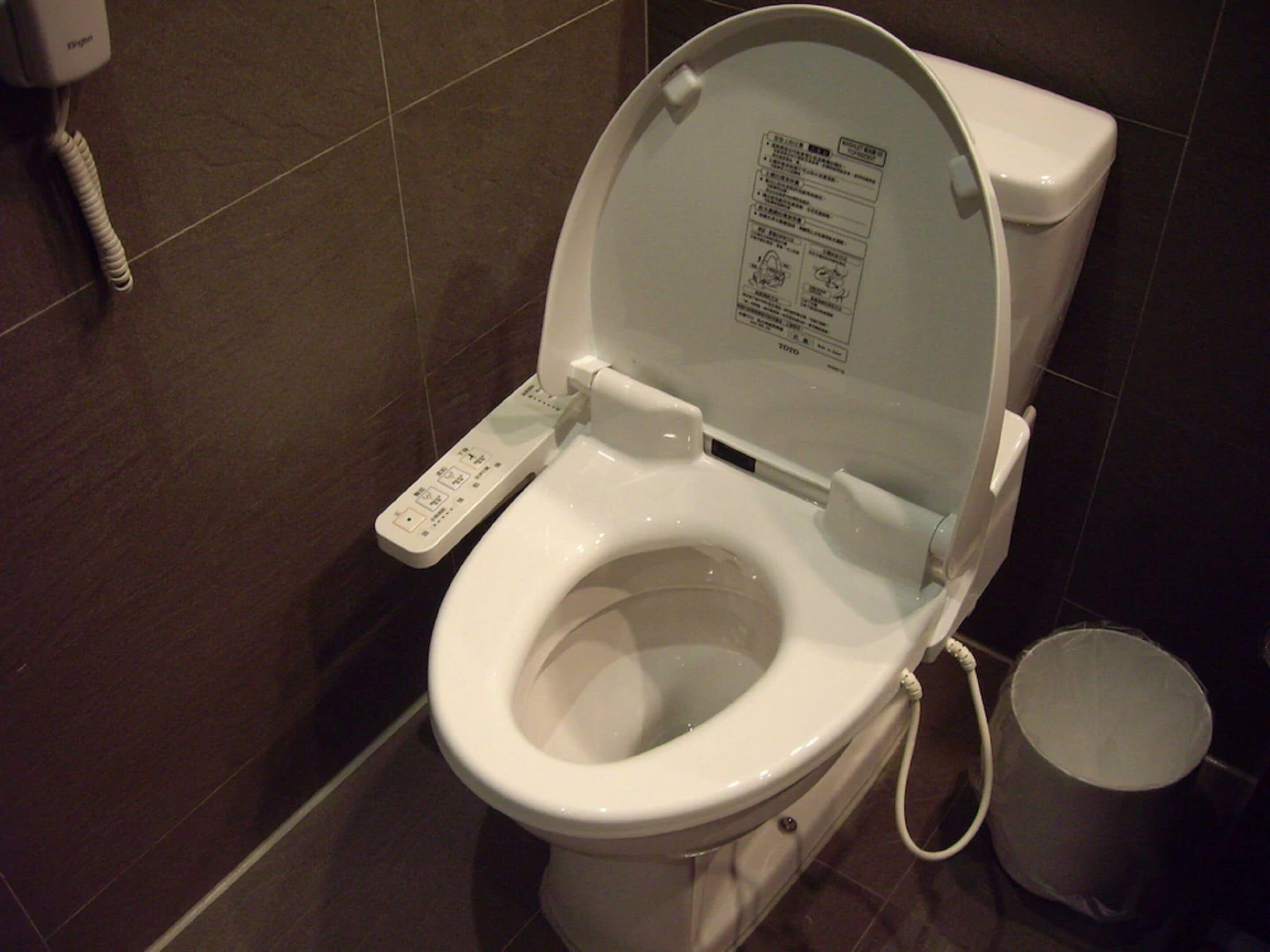 A modern toilet with a control panel and a bidet attachment.
