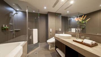 Un baño moderno con ducha envuelta en vidrio, una bañera, un inodoro y un tocador con lavamanos y espejo.