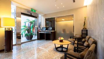 A modern lobby with a reception desk, seating area, and a large potted plant.