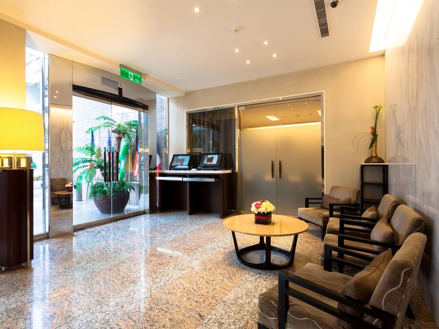 A modern lobby with a reception desk, seating area, and a large potted plant.