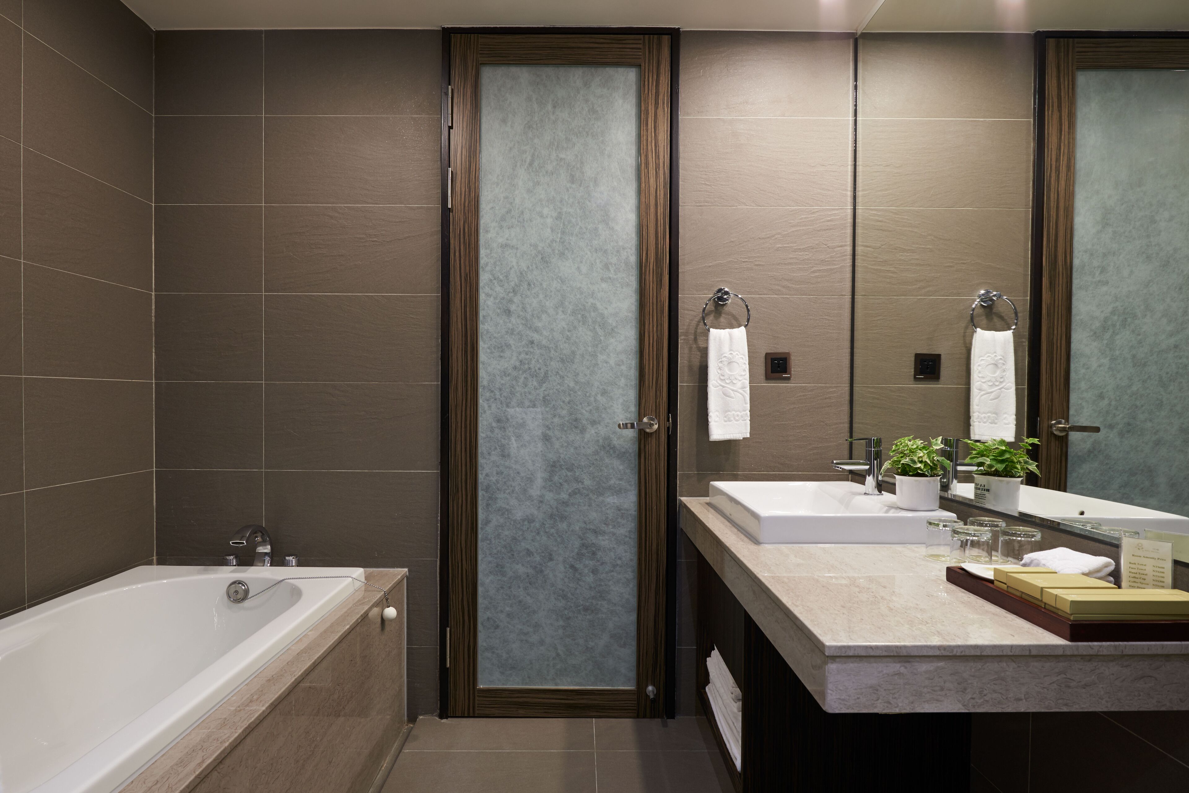 A modern bathroom with a bathtub, two sinks, and a large mirror.