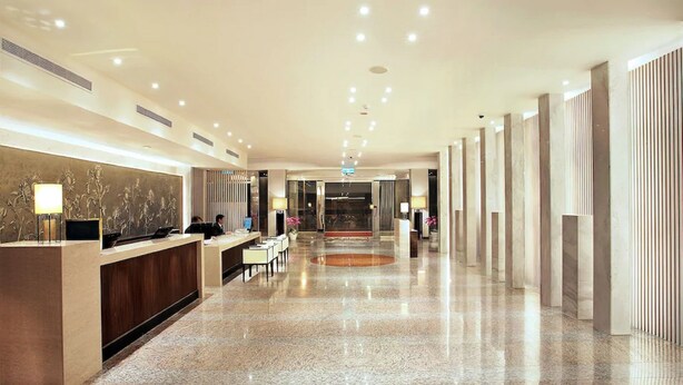 Una hall d'albergo con reception, area relax e un ampio pavimento in marmo lucido.