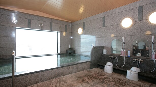 Ein modernes Badezimmer mit einer großzügigen, gläsernen Whirlwanne, Granit-Arbeitsplatten und einem Doppelwaschbecken mit Spiegeln.