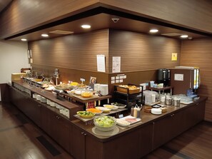Een buffetopstelling met diverse gerechten, een koffieapparaat en een koelkast.