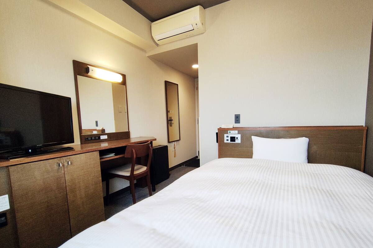 Une chambre d’hôtel équipée d’un lit, d’un bureau, d’une chaise, d’une télévision et d’un appareil de climatisation.