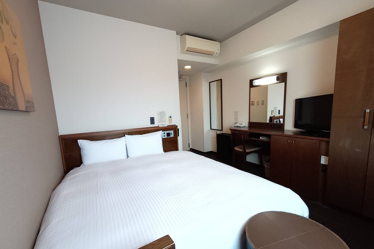 Une chambre d’hôtel avec un grand lit, un bureau avec une chaise, une télévision et une petite table.