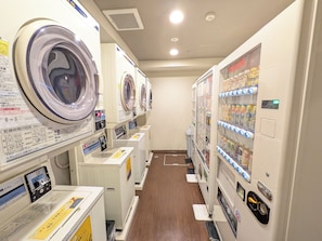 Une laverie équipée de plusieurs machines à laver et d’un distributeur automatique.