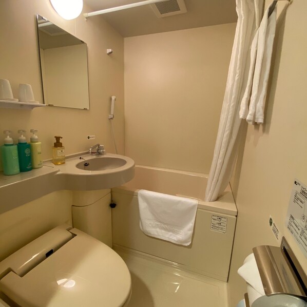 A bathroom with a sink, mirror, toilet, and shower curtain.