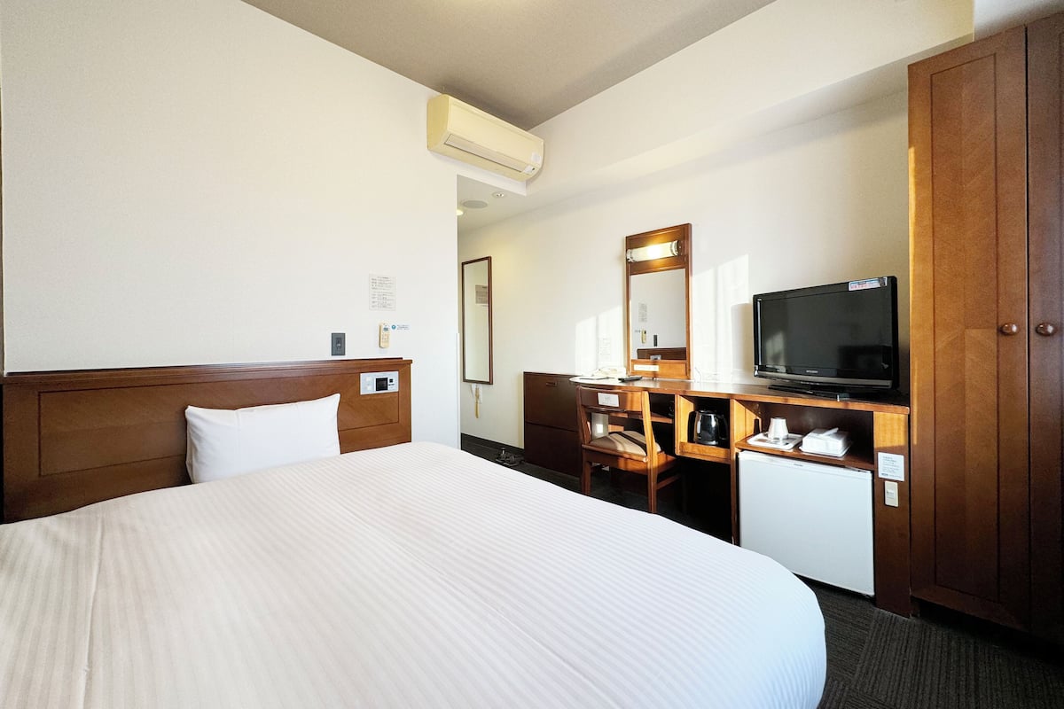Una habitación de hotel con una cama grande, un aparador de madera, un televisor y un espejo.
