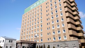 Un hotel a più piani con facciata uniforme, numerose finestre e un cartello verde in cima.