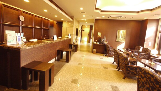 Una hall d'albergo con reception, area relax e un orologio a parete.