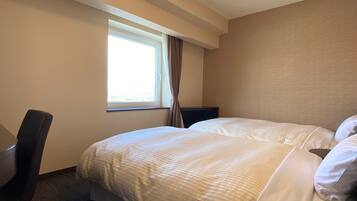 A hotel room with a large bed, a desk, and a window with curtains.