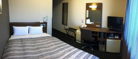 A hotel room with a bed, desk, chair, television, and a small refrigerator.