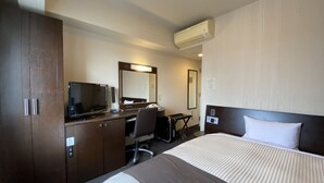 A hotel room with a bed, a desk with a computer, a chair, a desk lamp, a mirror, and an air conditioning unit. - Hotel Route-Inn Koriyama Inter (Koriyama)