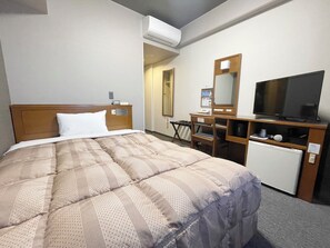 A hotel room with a bed, a desk, a television, and a mini-fridge.