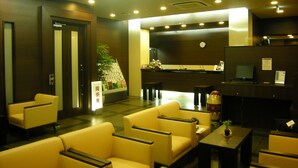 A hotel lobby with seating areas, a reception desk, and a clock on the wall.