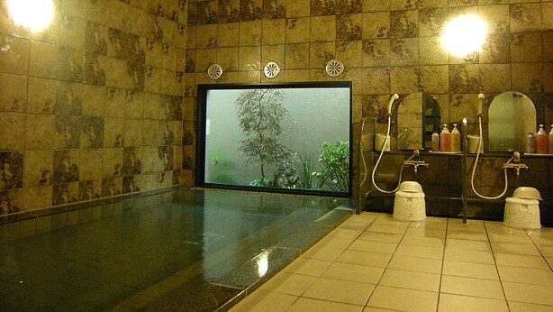 A spa room with a large glass wall, a wooden ceiling, and a tiled floor.