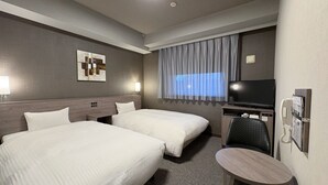 A hotel room with two beds, a desk with a chair, a television, and a phone.