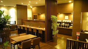 A restaurant with wooden flooring, multiple tables and chairs, a counter with a menu, and a plant in the center.