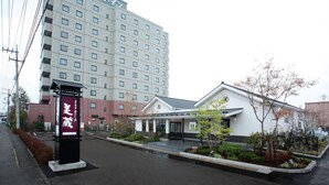 A hotel with a modern design, featuring a large building with multiple floors and a smaller annex building with a white facade and a sloped roof. - Hotel Route - Inn Nishinasuno (Nasushiobara)