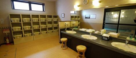 A restroom with multiple sinks, a mirror, and storage shelves.